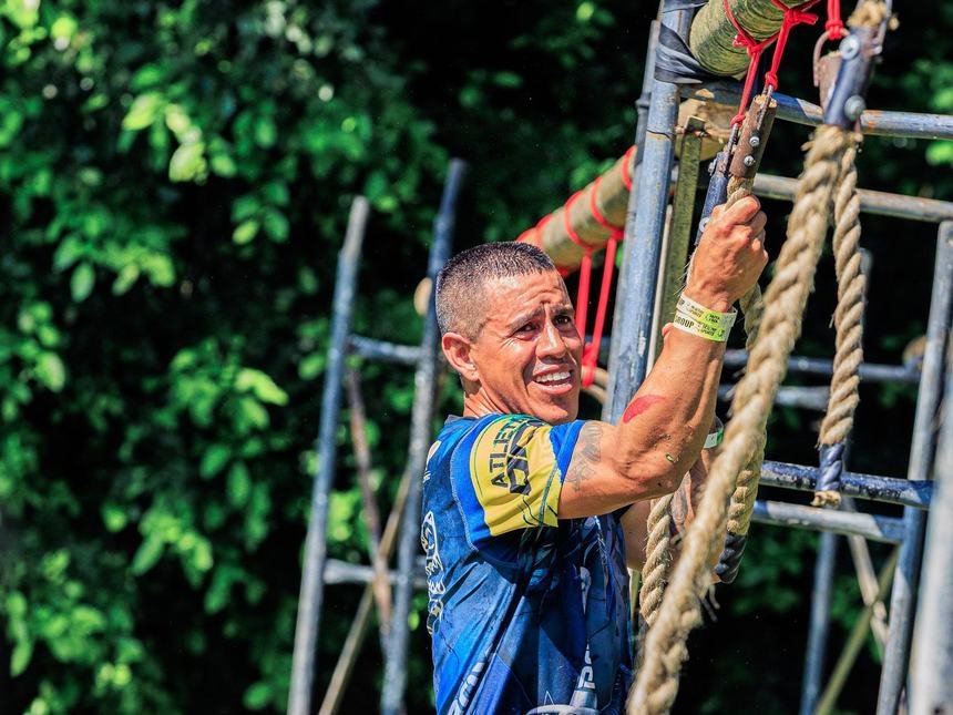 Athlete climbing a rope at an outdoor obstacle race